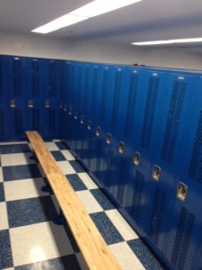 row of blue lockers with long bench in locker room