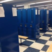 rows of blue lockers and benches in locker room
