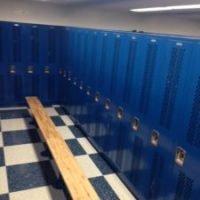 row of blue lockers with long bench in locker room